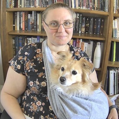 Kelsey sitting on a desk, with dog in lap facing the camera